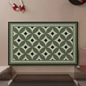 Grüne Fußmatte mit geometrischem Muster an einer Wand, davor ein Paar Schuhe