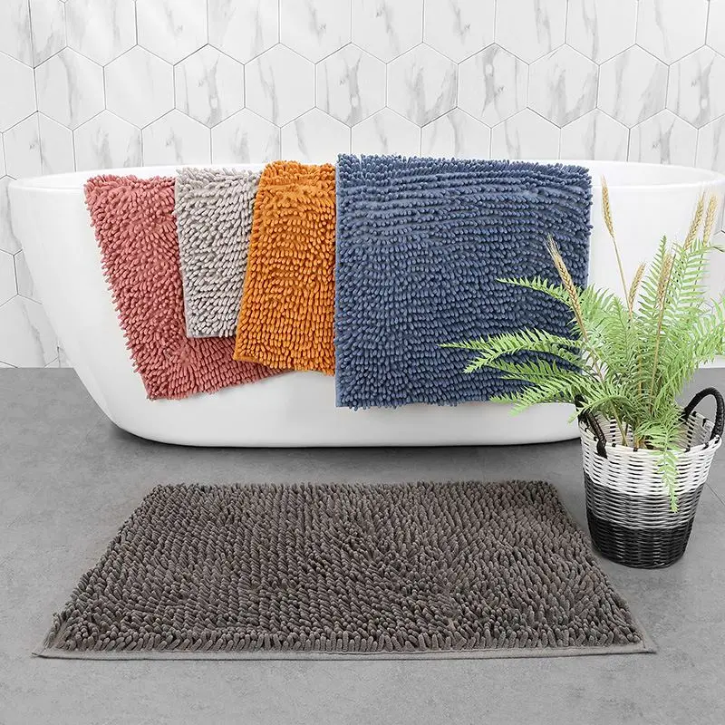Graue Chenille-Badematte mit weichen Noppen vor einer Badewanne