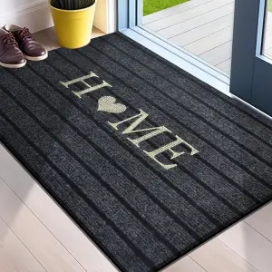Dunkelgraue gestreifte Fußmatte mit Schriftzug „Home“ in Beige vor einer Tür