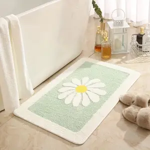 Hellgrüne Badematte mit weißer Gänseblümchen-Blüte und weißem Rand neben einer Badewanne
