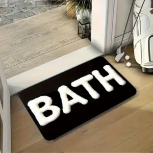 Schwarze Badematte mit weißem flauschigem BATH-Schriftzug vor einer Tür